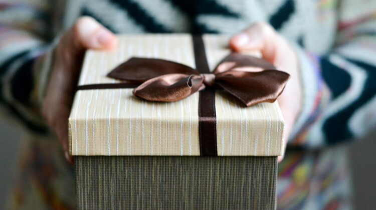 Hands holding a gift with a bow on it