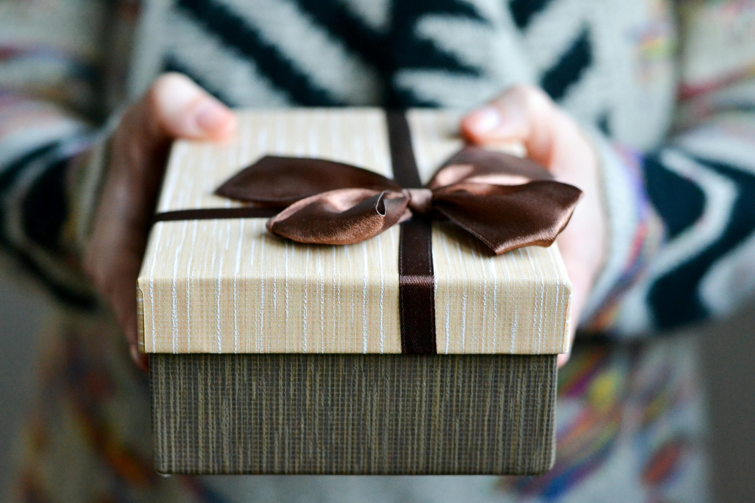 Hands holding a gift with a bow on it